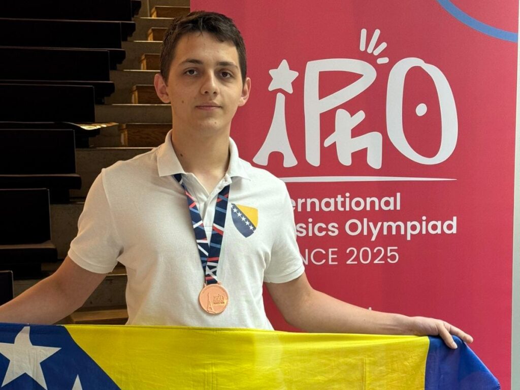 Muhamed Numanović holding the Bosnia and Herzegovina flag and wearing a bronze medal at the 2025 International Physics Olympiad in Paris.